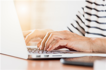 adult typing on a laptop